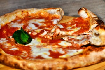 Close-up view of a neapolitan margherita pizza slices with buffalo mozzarella, tomato sauce and basil  on wooden background