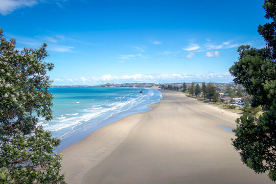 Beautiful white sand beach with blue sky and white puffy cloud at Orewa beach, Stunning views of a sunny day on the beach with clear sky, Coast Highway, Orewa, Auckland, New Zealand.
