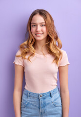 Fototapeta premium Young blonde female with wavy hair looking at camera, calm and smiling, in casual clothes, isolated on purple background. portrait
