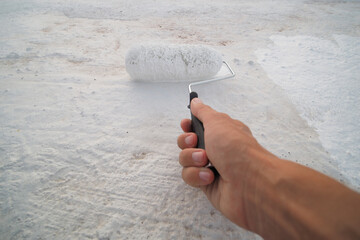 POV shot. Male hand holds roller and waterproofing roof..