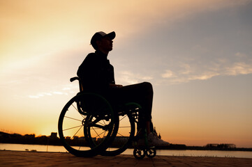 silhouette of a man in a wheelchair on the background of the sunset