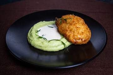 Kiev cutlet with mashed potatoes on a black plate