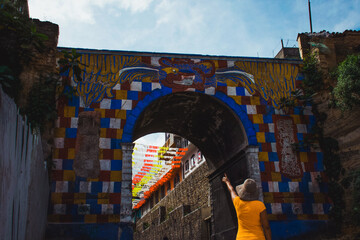 mujer joven señalando el arco Gucumatz ubicado en Chichicastenango Quiché Guatemala como destino turístico visitado durante las vacaciones - obrazy, fototapety, plakaty