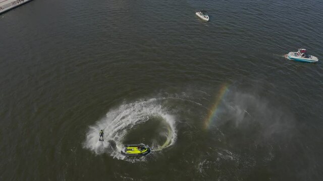 A man flies over the river on a flyboard and dives into the water. Flyboarding is a new extreme water sport. a man performs tricks in flight. Spectacular sports coups and turns. aerial view