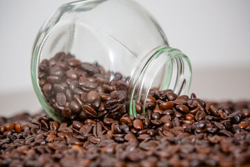 Grãos de café recém-retirados da fazenda espalham-se sobre a mesa, com o pó fino derramando-se do vidro. O aroma fresco e intenso preenche o ambiente.