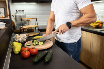 Close up of man cutting vegetables with a knife in his apartment