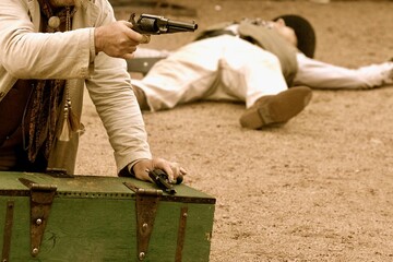 A sepia toned close up view of a cowboy ready to fire a handgun during a Wild West showdown in the...