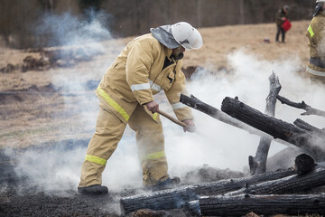 firefighters on the ashes. completed work on extinguishing the fire. analysis of the rubble of burnt pieces of wood on the site of the burned house. smog and the smell of burning