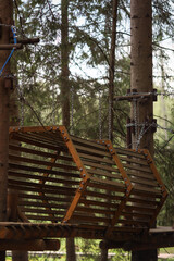 Sports park in the forest.Extreme outdoor recreation.Wooden elements,steps and ropes make up the route between the trees.Hanging ladders in the rope park.Rope park for children and adults