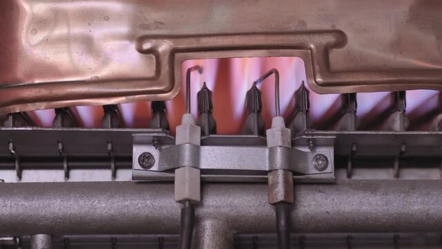 Gas flame igniting inside the gas heater inside the boiler.Heat exchanger and burner close up. 