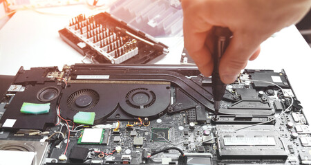 Laptop repair in a workshop, male hand holds a screwdriver
