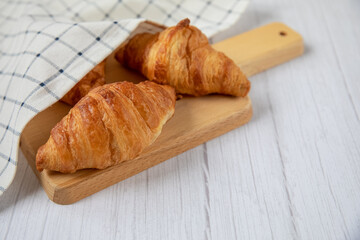 Concept food. Delicious fresh croissants on a wooden board. Light background.