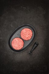 Raw Minced Homemade Grill Beef Burgers in Frying Pan, Top View. Griddle Grill Pap and Ground Beef Meat Patties for Grilling on Black Background, Overhead View. Raw Steak Burgers Cutlets On Grill Pan.