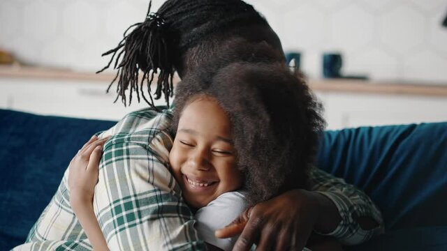 Father and daughter connection. Close up of happy smiling african american man and little girl hugging at home