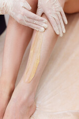 depilation master applies sugaring paste to the legs