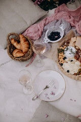 picnic table setting and decorations. picnic snacks and wine in clear glasses. champagne in transparent glasses on a white picnic blanket top view.