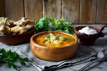 Hot soup with chicken and cabbage in a wooden plate on a gray table. Russian soup