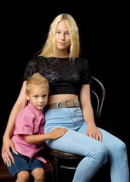 Younger Brother With Older Sister In The Studio On A Black Background.