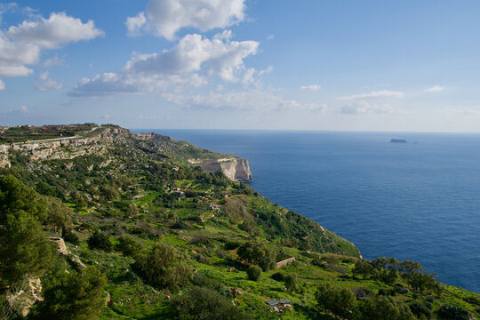 DINGLI CLIFFS, MALTA - JAN 02nd, 2020: Sea coast of Malta with Dingli Cliffs and Fifla Island in the background. Scenic high rising cliffs with panoramic view