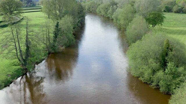 Aerial drone view flying low along a fast flowing brown river