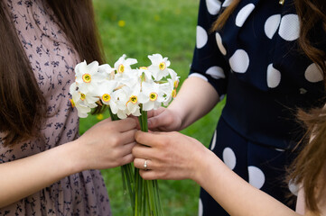 Three girls holding white and fragrant daffodil flowers
