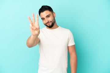 Young arab man isolated on blue background happy and counting three with fingers