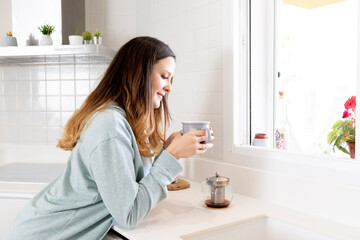Young girl looking at a cup of tea or coffee in the morning with window light.