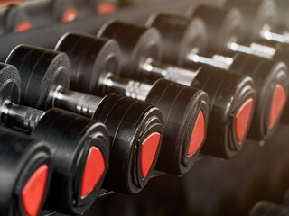Rack with many different sizes of dumbbells in the gym. Free weights zone. Focus blur. Copy space