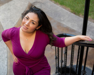 Hispanic latina model in a purple pink dress smiling and posing in location for a fashion portrait photoshooting  as a Mexican woman beauty concept