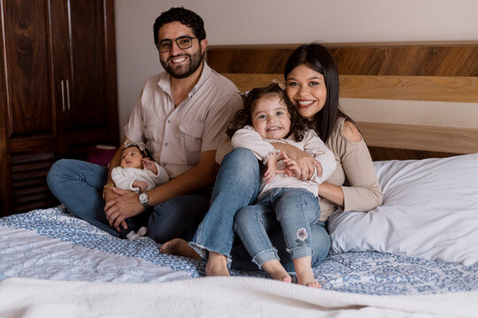 Home portrait of Hispanic family resting in bed - Latino family having fun at home