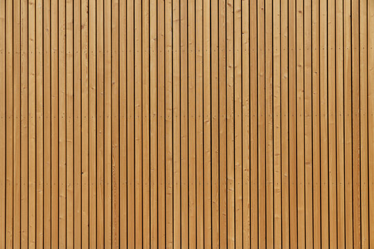 Facade sheathing made of wooden vertical planks. Warm yellow color.