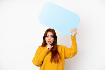 Young redhead woman isolated on white background holding an empty speech bubble and doing silence gesture