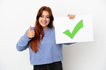 Young redhead woman isolated on white background holding a placard with text Green check mark icon with thumb up