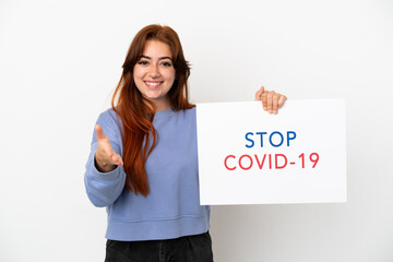 Young redhead woman isolated on white background holding a placard with text Stop Covid 19 making a deal