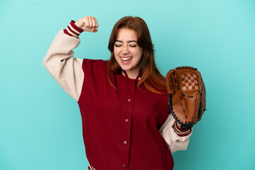 Young redhead woman playing baseball isolated on blue background doing strong gesture