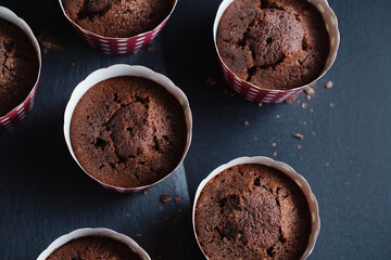 Appetizing muffins in cups on dark