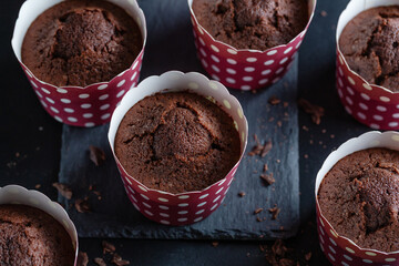 Appetizing muffins in cups on dark