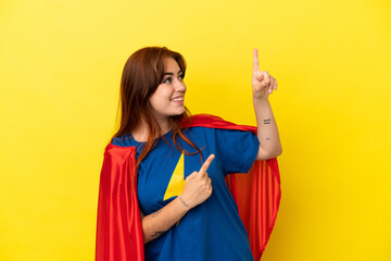 Super Hero redhead woman isolated on yellow background pointing with the index finger a great idea