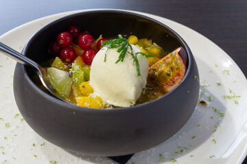Fruit salad with ice cream in a black bowl at a restaurant