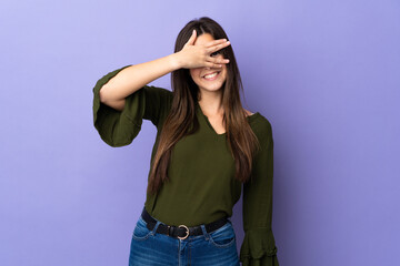 Teenager Brazilian girl over isolated purple background covering eyes by hands and smiling