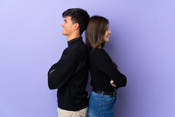 Young couple over isolated purple background keeping arms crossed