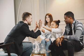Pshecoterapist clapping hands with little girl at family consultation