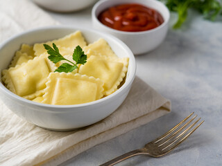 Close-up is a white plate with mouth-watering ravioli garnished with a sprig of parsley. Also in the frame is a gravy boat with brown sauce. White background. Pastel shades.