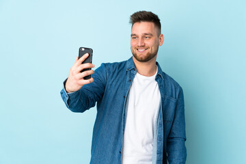 Russian handsome man isolated on blue background making a selfie