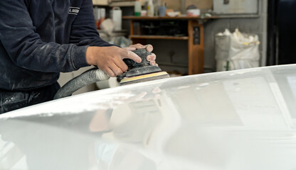 Young man sanding the hood of a giant car. Madrid