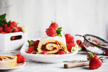 Homemade strawberry shortcake cake roll or Roulade with a berry jam filling and powdered sugar with...