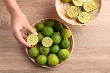 Fresh bergamot fruit in a basket holding by woman hand on wooden background, Food ingredients and extract used for medicine, tea, perfumes and cosmetics