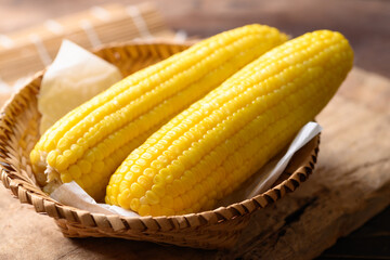 Sweet corn cob in a bamboo basket on wooden background