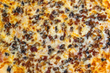 Close-up of pizza with ham, bechamel sauce, mushrooms, bacon and cheese.