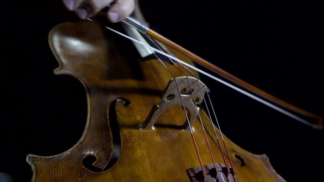 Cellist playing legato notes in slow motion. Close up of bow and fingers.